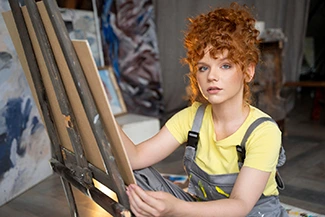 A woman with red hair sits on an easel, symbolizing women's transformative contributions to art and culture.